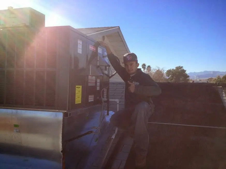 HVAC technician performing AC Tune-Up on a rooftop unit in Stoneham